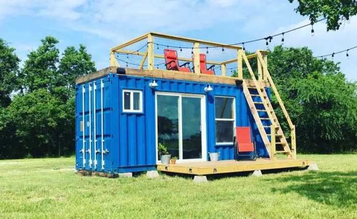 A two-storey green shipping container home with exterior stairs, built from the containers Van Blanc supplies for tiny homes and cabins in Ontario.