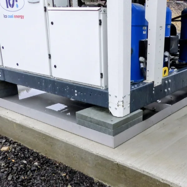 Industrial chiller unit levelled on two stacked recycled-plastic corner pads on a concrete slab