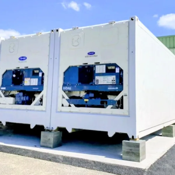 Three refrigerated shipping containers sitting on stacked recycled-plastic corner pads