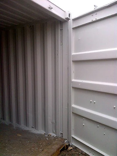 A sealed, painted container interior corner, the wipe-down surface an aging room is finished to.