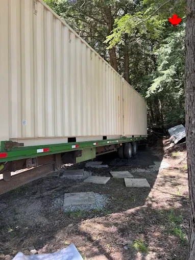 A container settled onto blocking at the end of a rural laneway