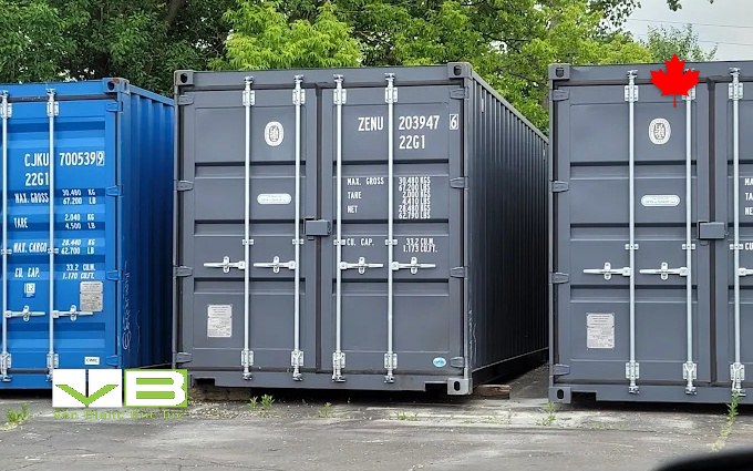 Dark grey twenty-foot units standing door-end out along the yard aisle, a blue container closing the row.
