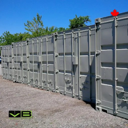 A long row of grey units standing side by side on gravel under summer trees.