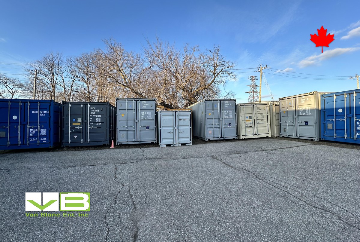 Rows of 20ft units in mixed colours and grades lined up on yard asphalt under a clear sky.