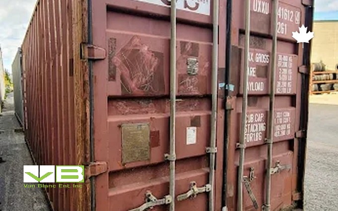The door end of a weathered rust-red container, patina even across the corrugations, data plate still legible.
