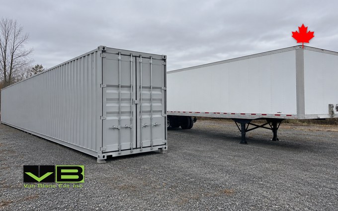 A plain grey 53 foot domestic shipping container resting on the ground next to an unmarked white 53 foot dry van trailer on its landing gear, parked side by side on a gravel yard so the matching lengths line up