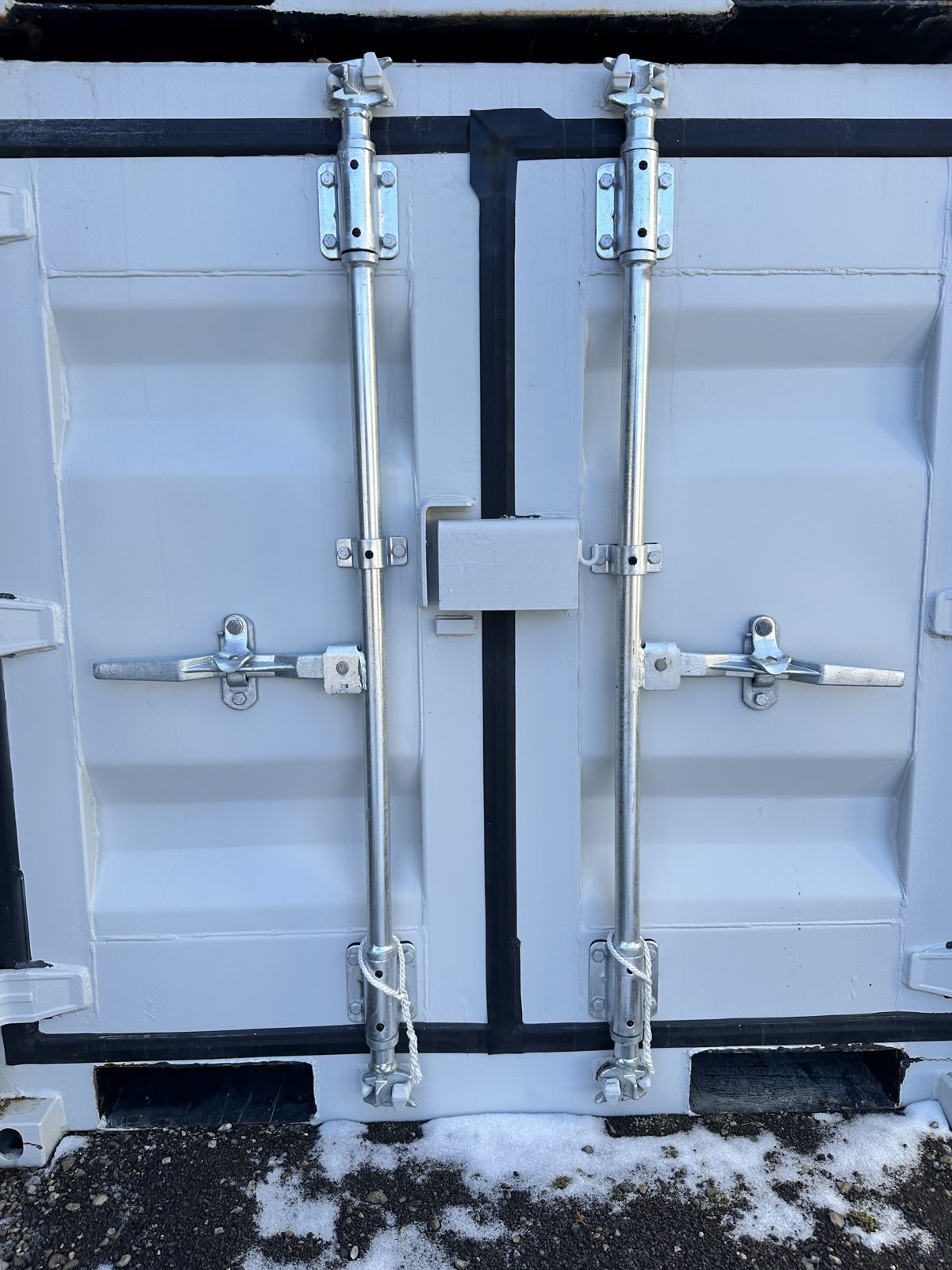 Double cargo doors on a light grey 5'7" mini with galvanized locking bars, a welded lockbox between the doors and two fork pockets at the base