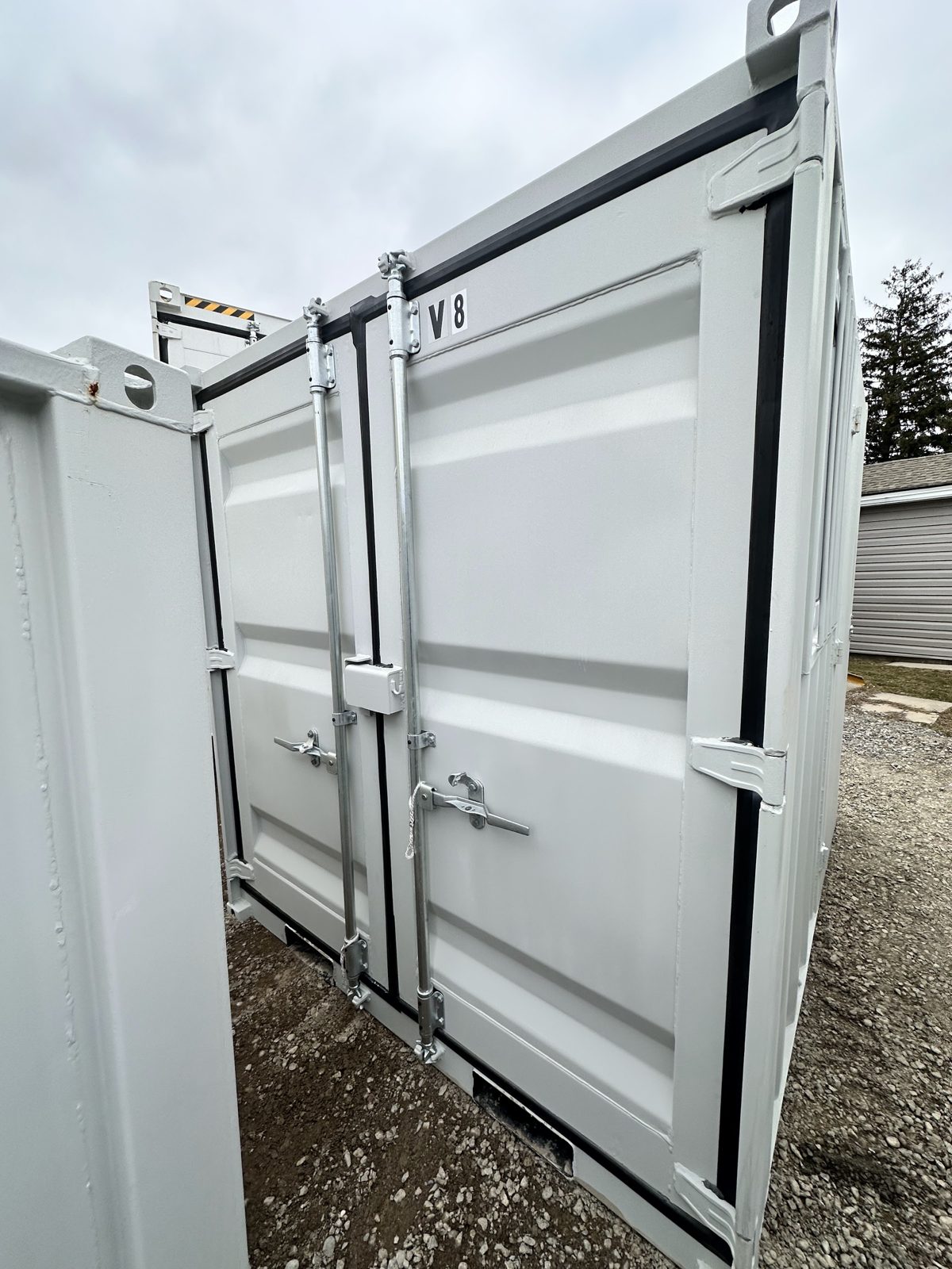 Two grey cargo doors on an 8 foot container, each with a galvanized locking bar, a lockbox on the centre seam and fork pockets in the bottom rail
