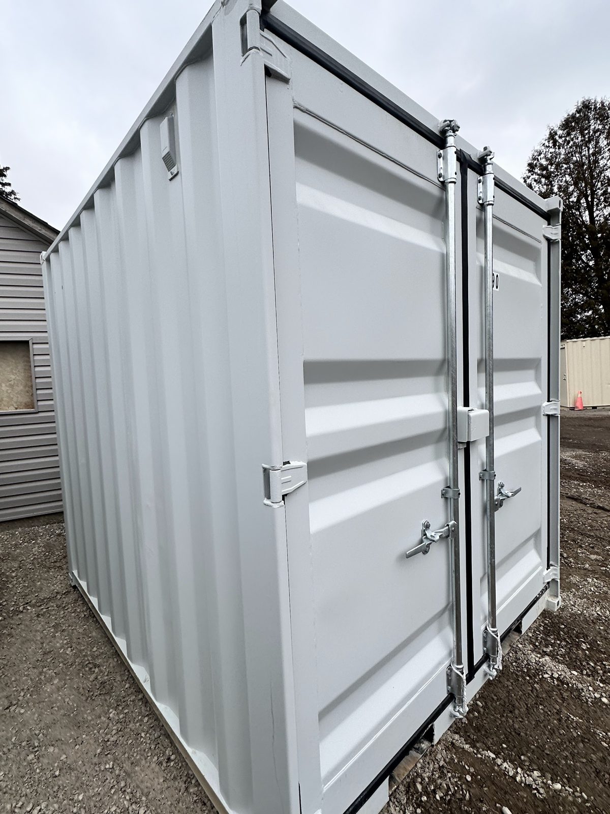 Plain side wall of a grey 9ft with a small louvred vent near the roof line, next to cargo doors with a lockbox at the centre seam