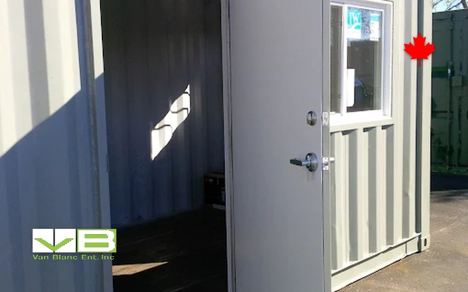 A converted shipping container fitted with a personnel door and a window, standing in the yard