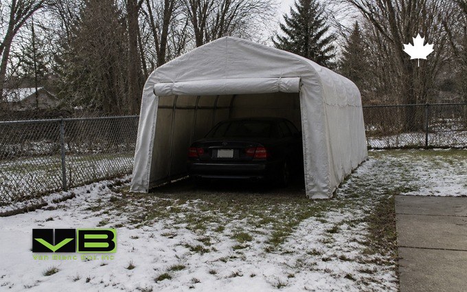 A white fabric portable garage sheltering a car on a snowy Ontario lawn with bare trees behind