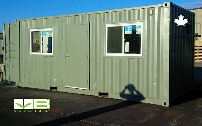 A green insulated container office with a steel man door and two framed windows standing on a yard, the foamed steel version of an insulated shed