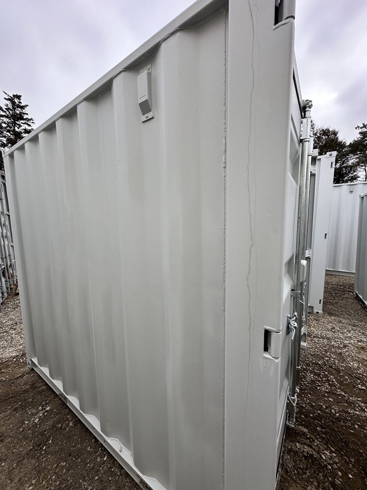 Plain corrugated side wall of the grey 8ft with a small perforated vent near the roof line and the cargo doors at the right