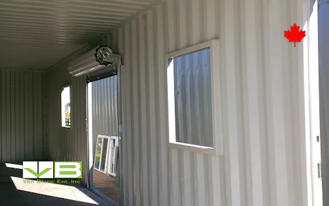The lined, insulated interior of a shipping container with a framed window and a door, the kind of room a cold plunge and sauna end up living in