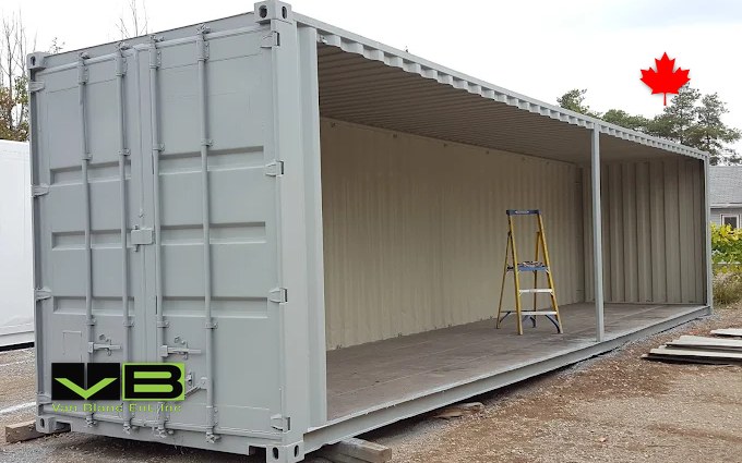 An open-side shipping container with its long side panels swung open, set up as a workshop bay