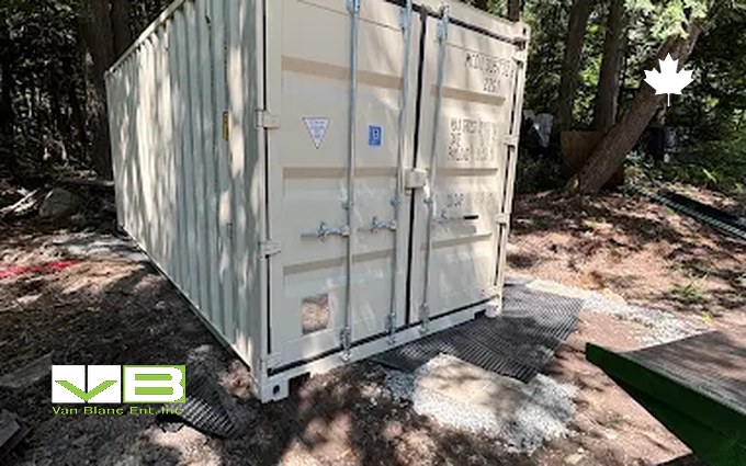 A tan one-trip 20-foot shipping container standing on the gravel lot with its doors closed