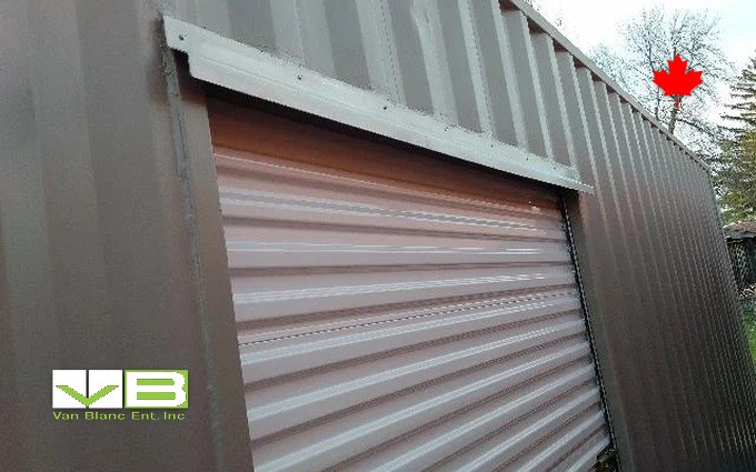 A white roll-up door installed in the end of a brown container, the drive-in conversion up close