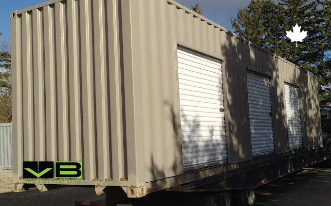 A tan 40-foot unit fitted with three white roll-up doors, riding a trailer out for delivery
